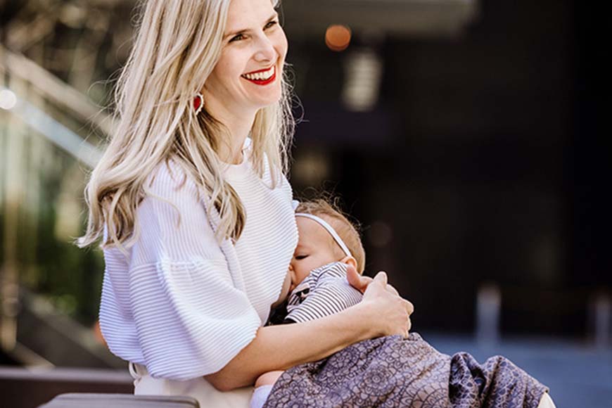 mother is breastfeeding her child while smiling
