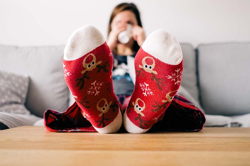 Frau legt Füße lässig auf dem Tisch ab und trinkt dabei Kaffee