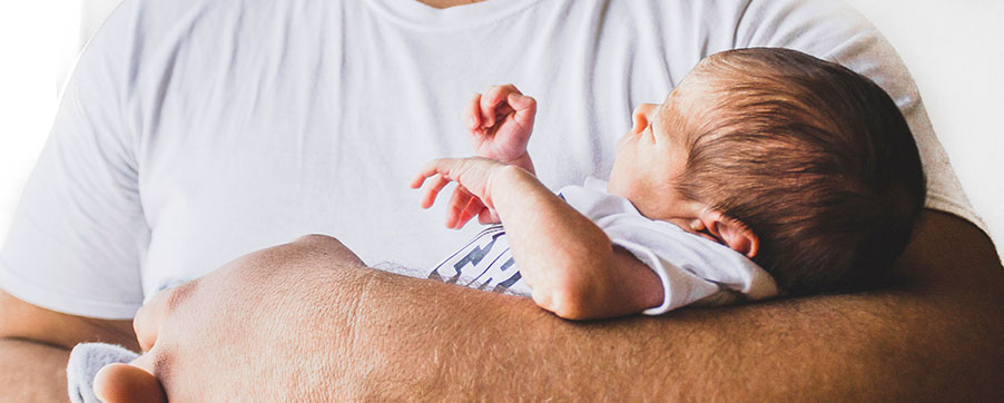 Ein Baby wird liebevoll auf dem Arm eines Mannes getragen