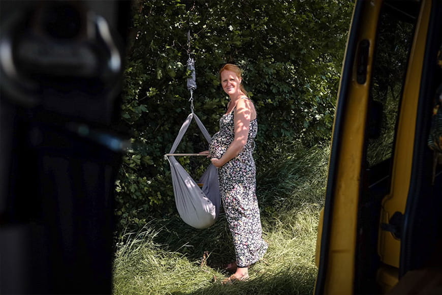 Woman standing outside in nature at a grey swinging hammock