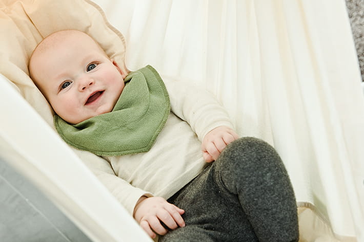 Baby lies in the Swinging Hammock and smiles into the camera