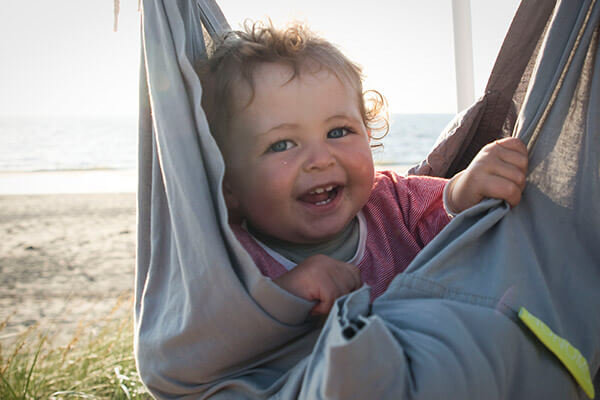 Baby on beach in the swinging hammock in grey