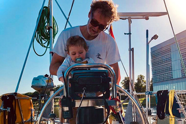 Baby is held by dad and both are at the steering wheel