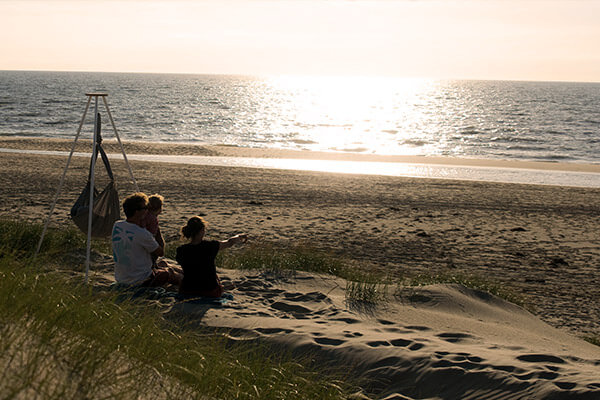 Family on the beach looking at the sea in the evening sun